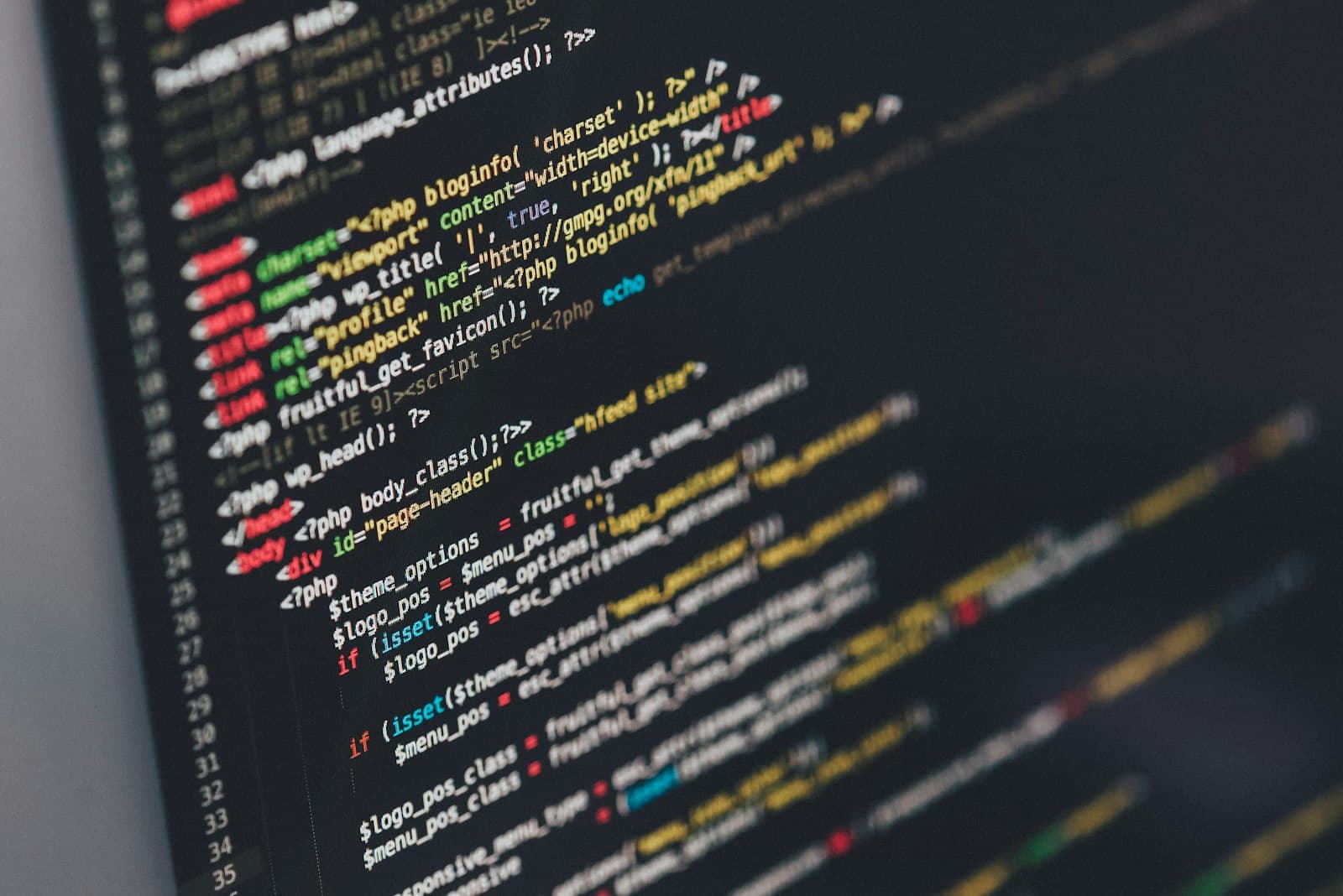 Close-up of a developer's laptop screen filled with source code, warm-lit workstation.
